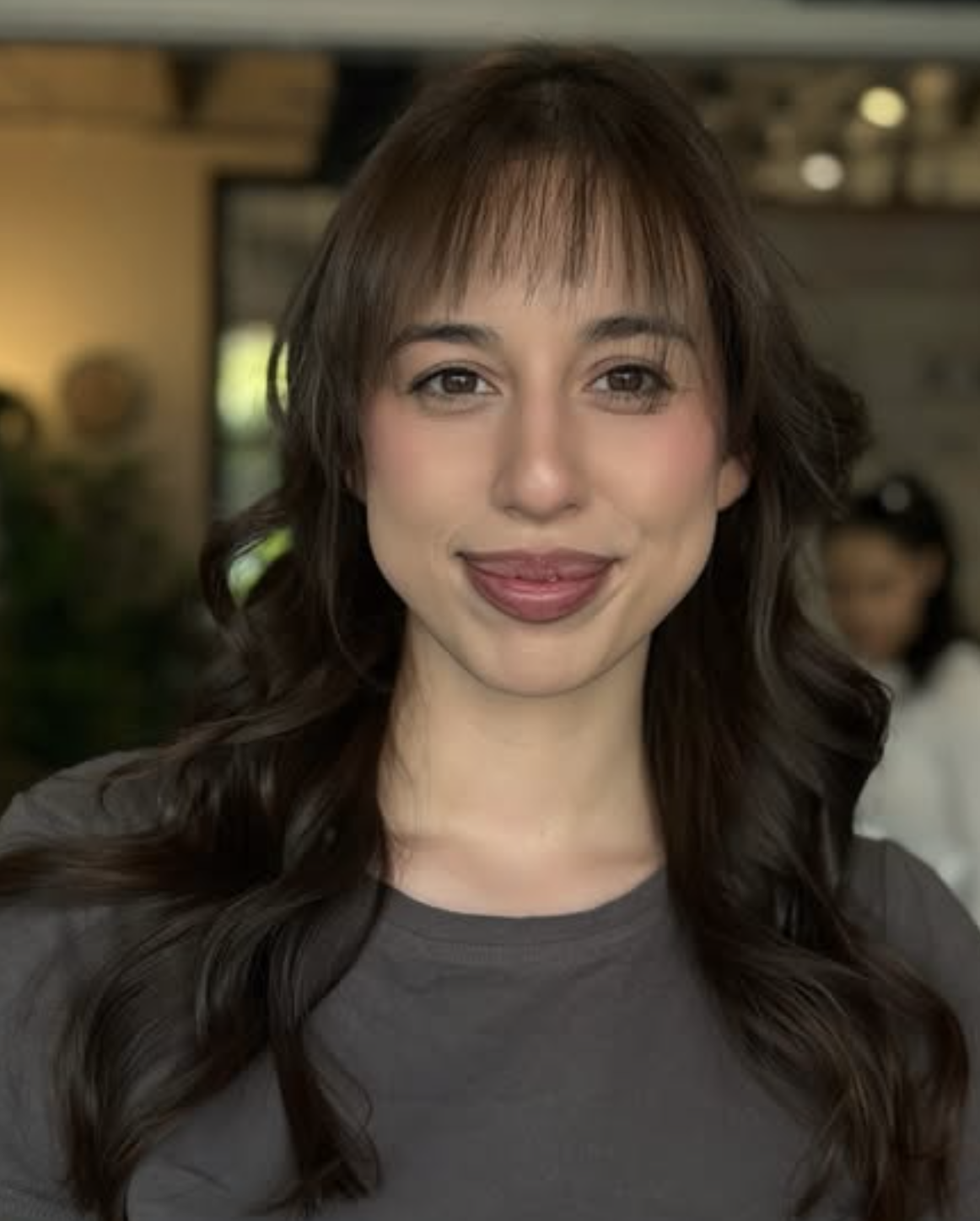 Client result featuring a polished brunette cut with soft bangs and loose waves.
